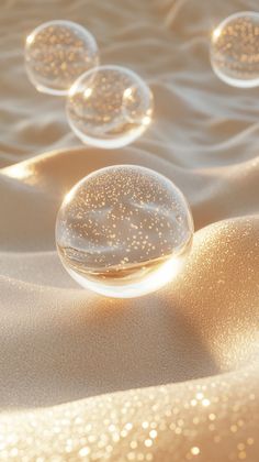 three bubbles floating in the air on top of sand covered with water and gold flecks