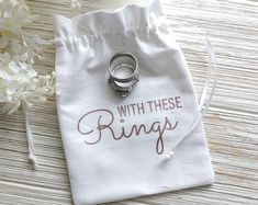 a ring sits on top of a white bag with the words, with these rings printed on it