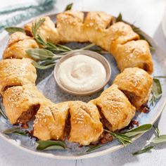 an appetizer is arranged on a plate with rosemary sprigs and dip