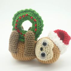 a small stuffed animal with a christmas wreath on its back, and a crocheted ornament in the shape of a slotter's head