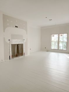 an empty living room with white walls and wood flooring is being painted in the same color as the rest of the room