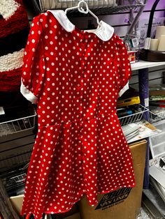 a red and white polka dot dress hanging on a rack in a room with other items