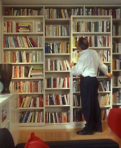 a man standing in front of a book shelf filled with books