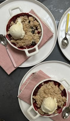 two white plates topped with fruit and ice cream on top of a table next to utensils