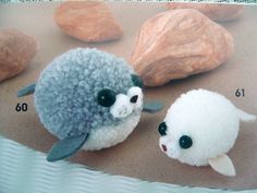 two small stuffed animals sitting next to each other on a sandy surface with rocks in the background