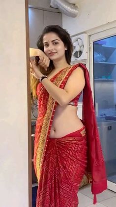 a woman in a red sari posing for the camera with her hands on her hips