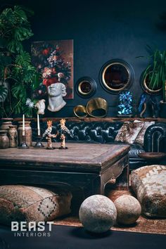 a living room filled with lots of furniture next to plants and pictures on the wall