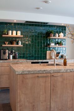 a kitchen with wooden cabinets and green tile backsplashing on the back wall