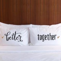 two pillows with the words she and him written on them sitting on a white bed