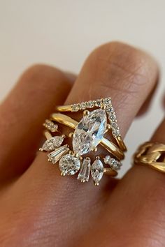 a woman's hand with two gold rings and an oval shaped diamond ring on it