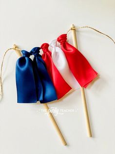 three small red, white and blue bows on wooden sticks