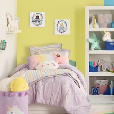 a child's bedroom with yellow walls and unicorn themed bedding, bookshelves and toys