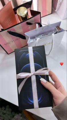 a person holding an open gift box in front of some boxes with perfumes on them