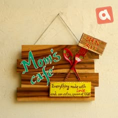 a wooden sign that says mom's cafe hanging on the wall next to a pair of scissors