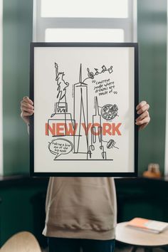 a person holding up a poster with the words new york written on it in front of them