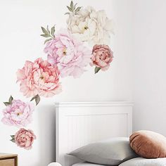 a white bed sitting under a pink flower wall decal