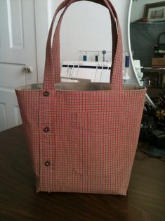 a red and white bag sitting on top of a wooden table next to a mirror