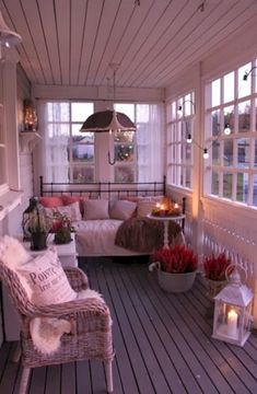 the porch is decorated with white furniture and candles