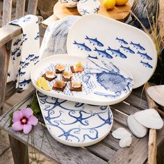 blue and white plates with food on them sitting on a wooden bench next to flowers