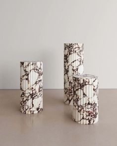 three white and black vases sitting on top of a table