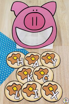 a pink pig is next to some cookies with the word happy on them and a blue polka dot table cloth