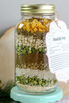 a glass jar filled with different types of food on top of a wooden table next to a sign