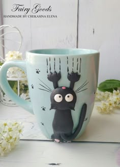 a coffee cup with a black cat on it's face and paws painted on the side