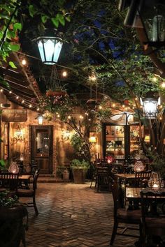 an outdoor restaurant with tables and chairs lit up at night