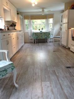 an empty kitchen with white appliances and wood flooring in the middle of the room