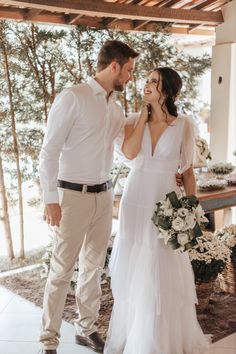 a man and woman standing next to each other in front of a table with flowers