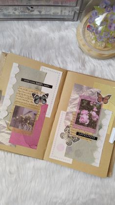 an open scrapbook with butterflies and flowers on it sitting on a white furnishing