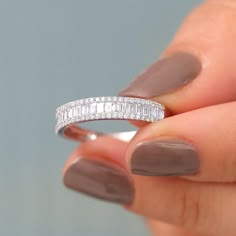 a woman's hand holding a ring with diamonds on the middle and bottom of it