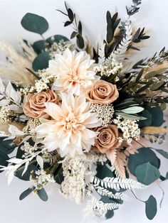 an arrangement of flowers and greenery on a white background