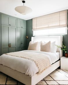 a bedroom with green painted walls and white bedding in the center, along with an area rug on the floor