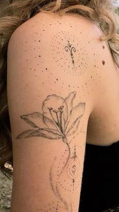 a woman's arm with a flower tattoo on the back of her left shoulder