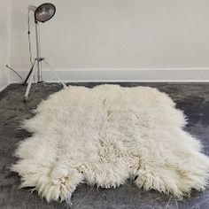 a white sheepskin rug on the floor next to a lamp