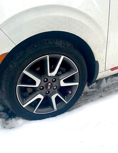 a white car parked in the snow with it's tire up close to the ground