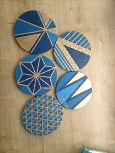 four blue and gold coasters sitting on top of a wooden table