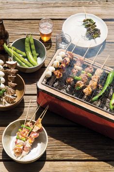 there are many food items on the grill and plates with skewered meats