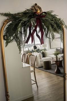 a living room decorated for christmas with greenery on the mantle and gold framed mirror