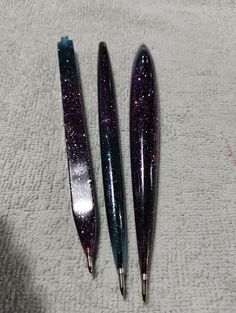 three shiny pens sitting on top of a white towel