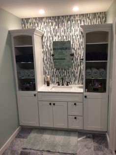 a bathroom with white cabinets and marble flooring