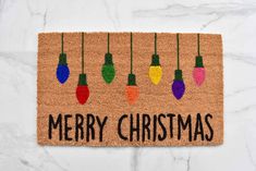 a door mat with christmas lights hanging from it's sides and the words merry christmas