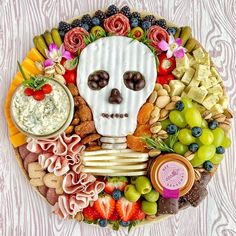 a platter with fruit, crackers, cheeses, and a skull face on it