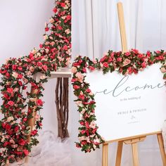 a sign with flowers on it sitting in front of a white backdrop and some wooden easers