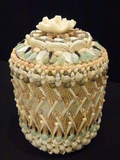 a decorative box with shells and seashells on the lid sits on a black surface