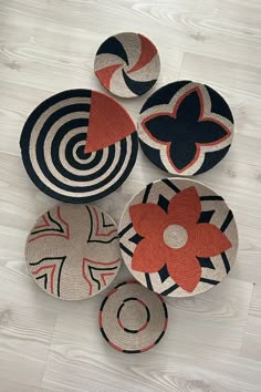 four black and white baskets with red flowers on them sitting on a wooden floor in front of a wall