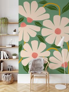 a chair sitting in front of a wall with flowers painted on it and bookshelves