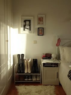 shoes are lined up on a shelf next to a bed in a room with white walls