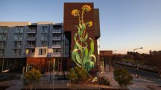 a tall building with a mural on the side of it's face and flowers painted on the side